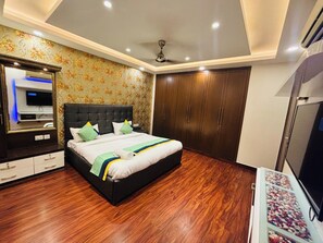 Quarto com cama, guarda-roupa e televisão.