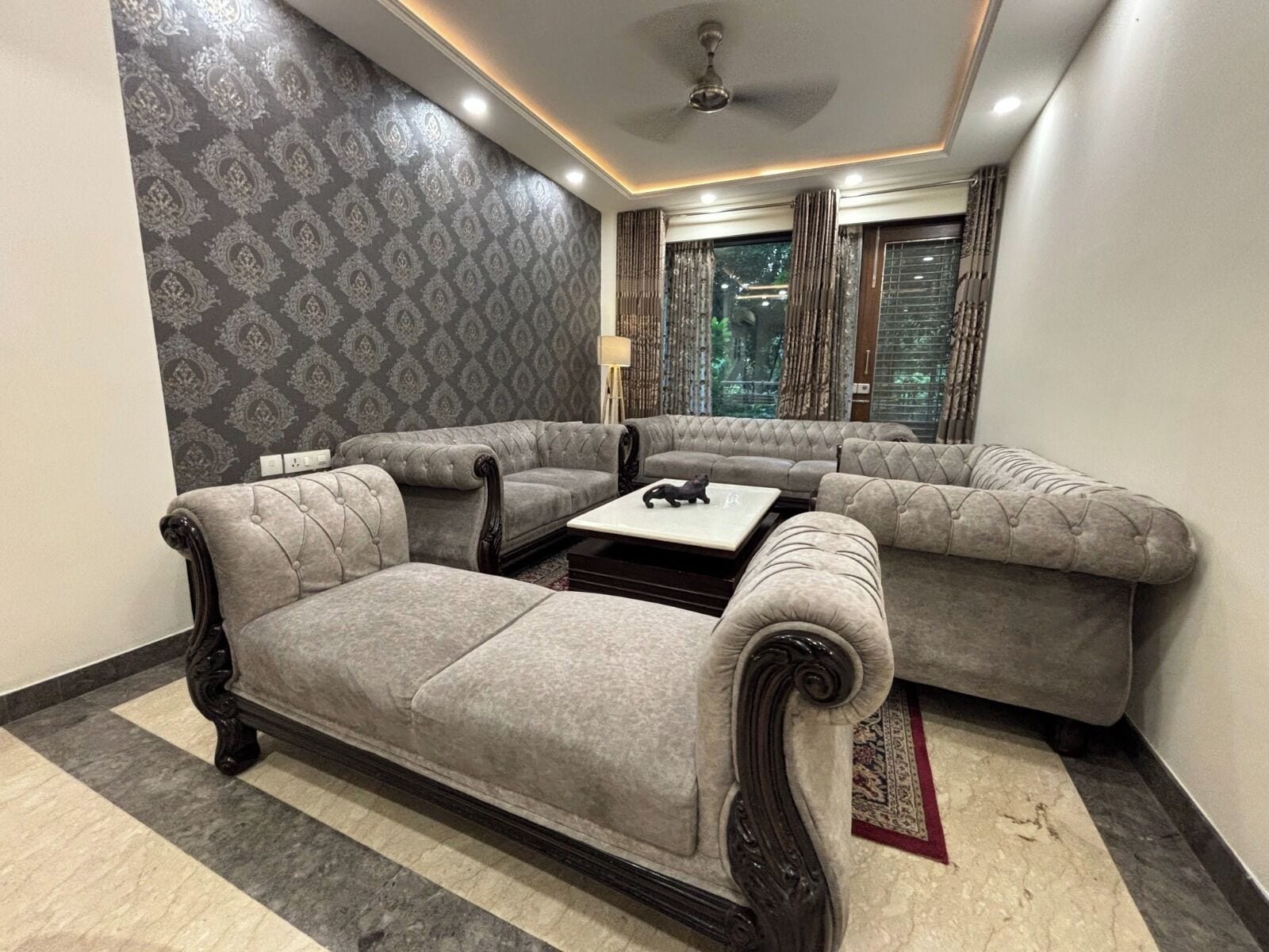 Un salón con un sofá modular, una mesa de centro y un papel tapiz estampado.