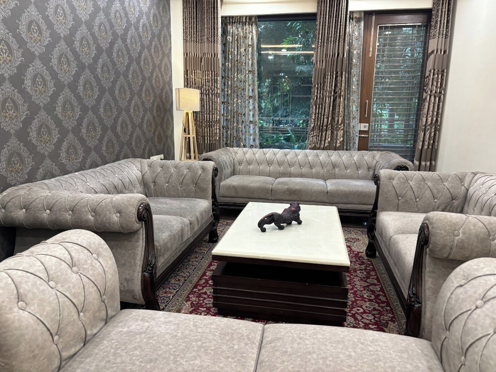 A living room with a grey sofa set, a coffee table, and a patterned carpet.