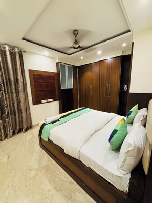 Un dormitorio con cama, cortinas, ventilador de techo y armarios de madera.