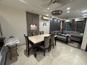 Espaço de estar moderno com área de jantar, sofá e detalhe decorativo na parede.