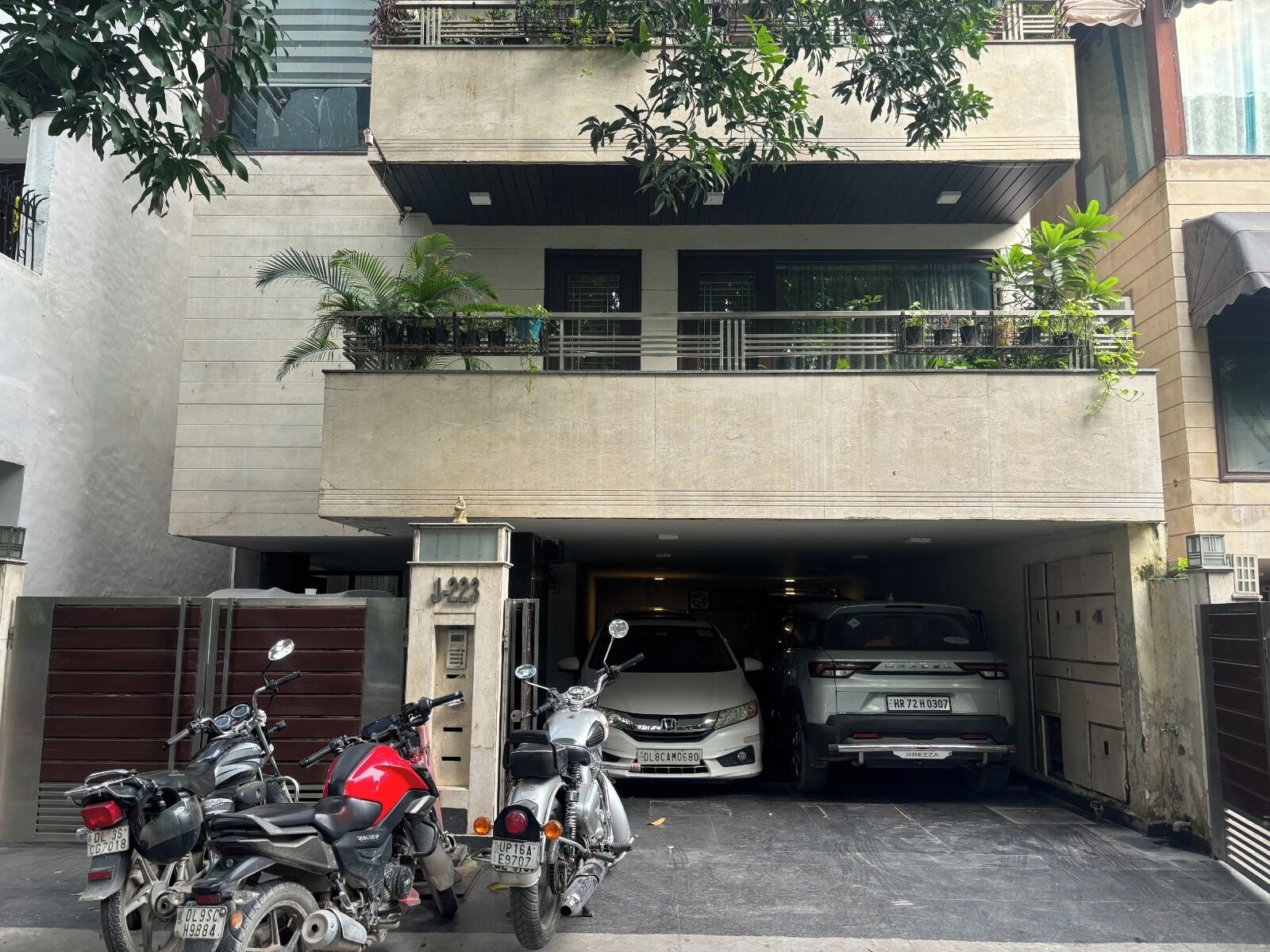 A multi-story building with a garage entrance, parked motorcycles, and a car.