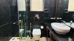 Un baño moderno con ducha de vidrio, inodoro blanco y un lavamanos grande.