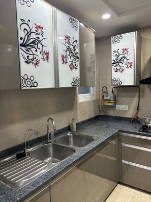 Una cocina con un lavamanos doble, gabinetes de acero inoxidable y una encimera de granito.