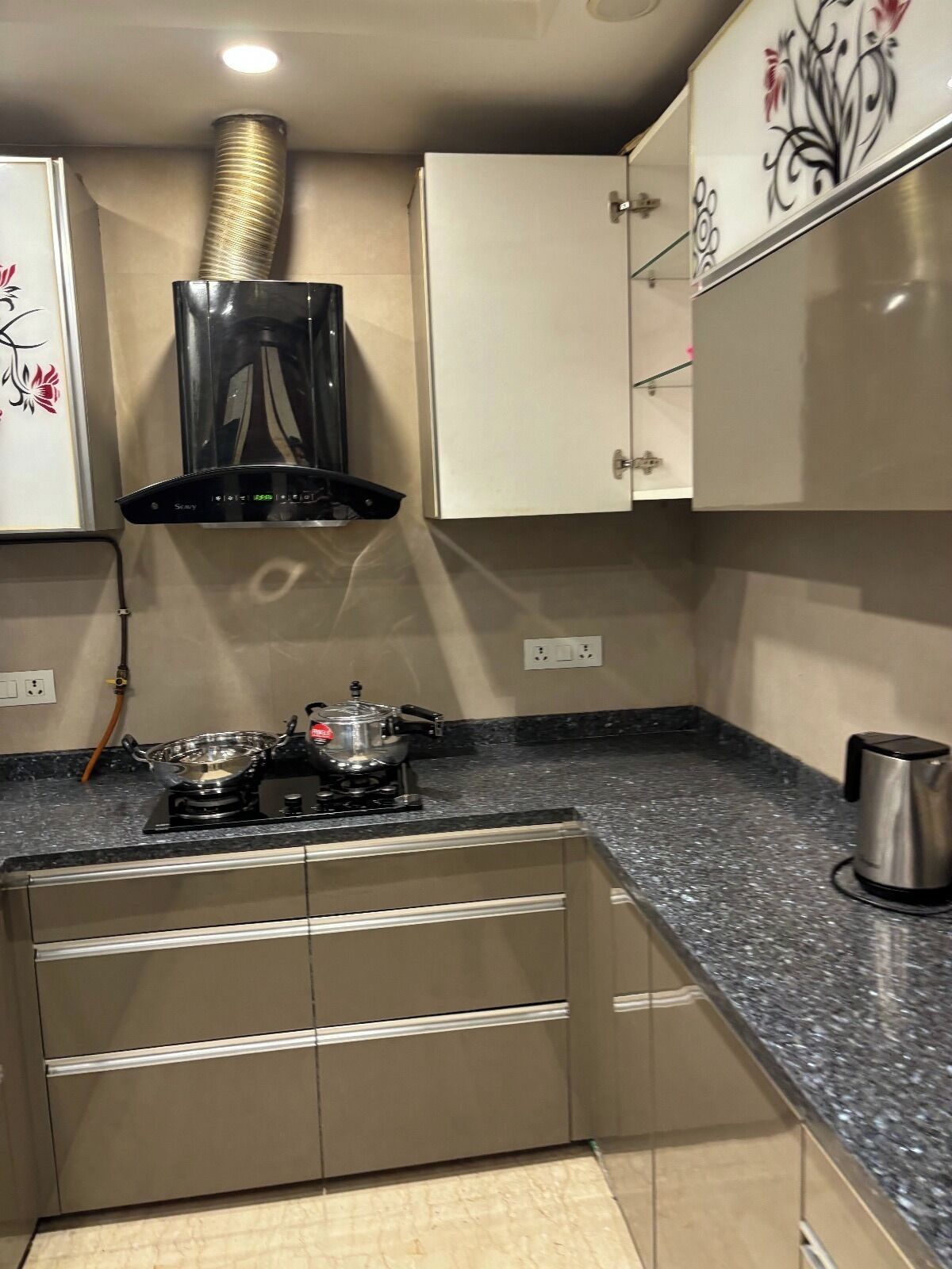 Una cocina con estufa a gas, cafetera y tetera de acero inoxidable sobre la encimera.