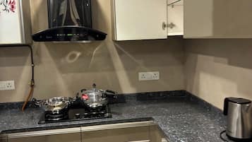 Una cocina con estufa a gas, cafetera y tetera de acero inoxidable sobre la encimera.