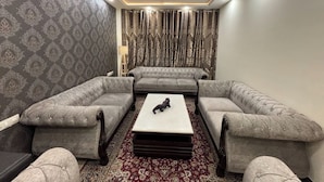 Una habitación con un conjunto de sofás, una mesa de centro, papel tapiz estampado y cortinas.