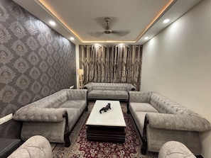 Quarto com sofá, mesa de centro, papel de parede estampado e cortinas.
