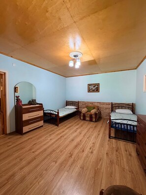 A bedroom with two single beds, a wooden dresser, a mirror, and a ceiling fan. - Şəki triohomesheki (Şəki)