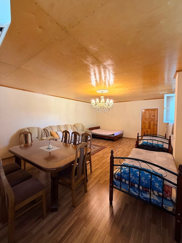 A cozy room with a wooden ceiling, a dining table with chairs, a sofa, a bed with a metal frame, and a chandelier. - Şəki triohomesheki (Şəki)