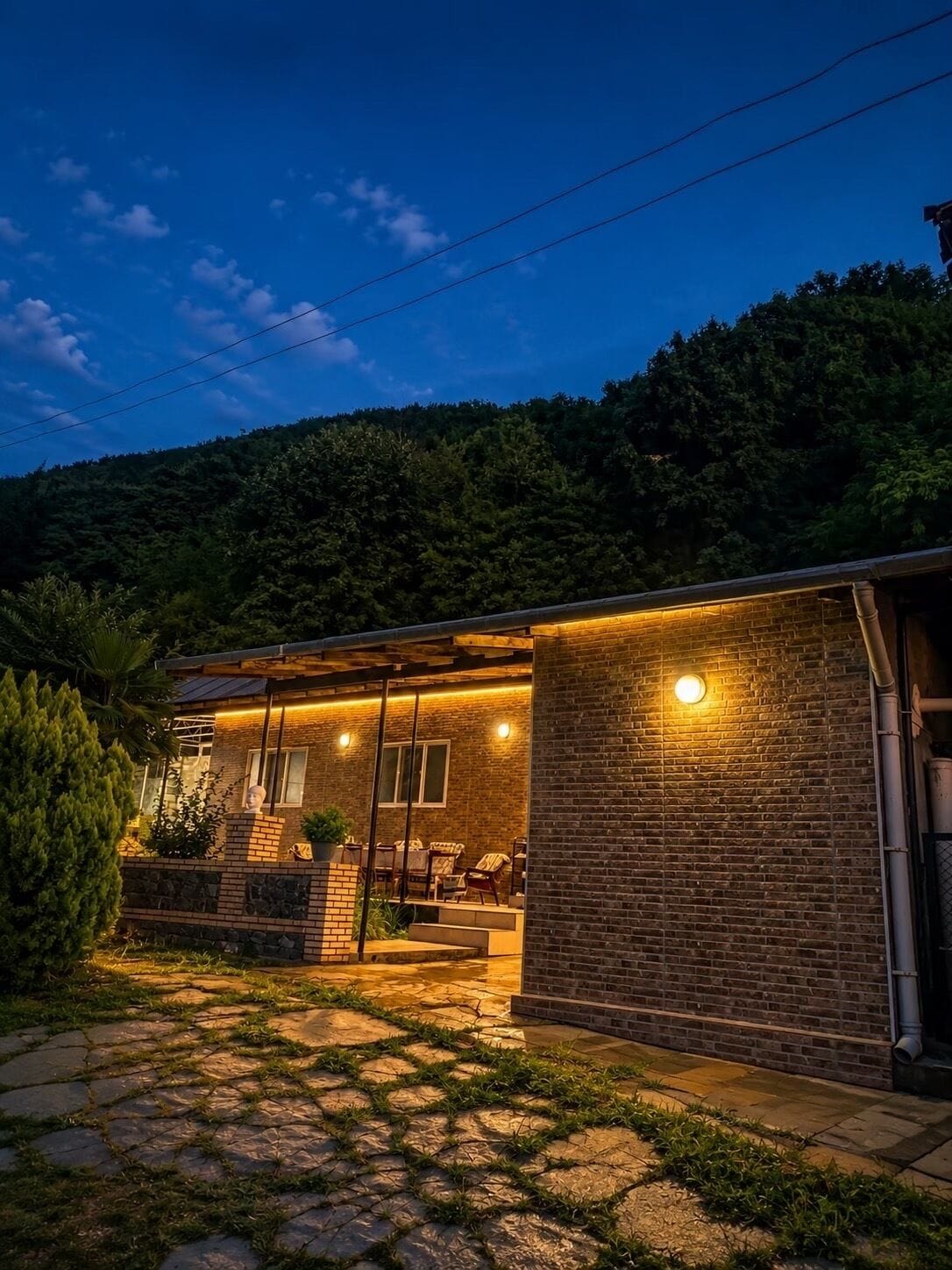 A modern house with a brick exterior, a glass door entrance, and a patio area with outdoor furniture.