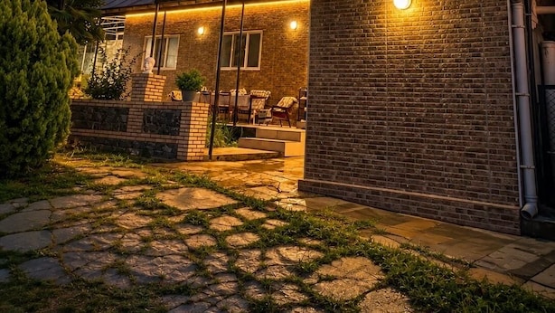 A modern house with a brick exterior, a glass door entrance, and a patio area with outdoor furniture.