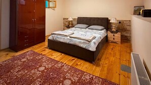 A bedroom with a bed, a wardrobe, a radiator, and a ceiling fan.