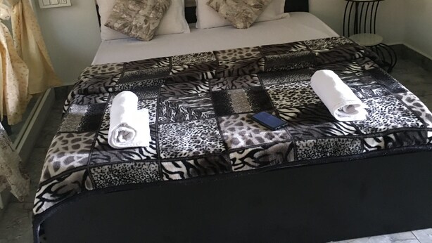 Ein Bett mit einem gemusterten Überwurf, zwei Kissen, ein kleiner runder Tisch und ein Handtuch auf dem Bett.