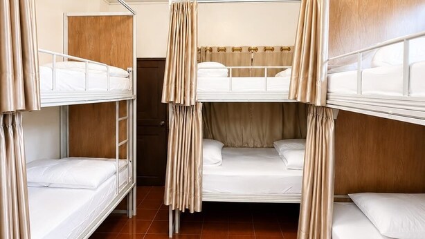 Una habitació amb lliteres, un panell de fusta al capçal i una làmpada al sostre.