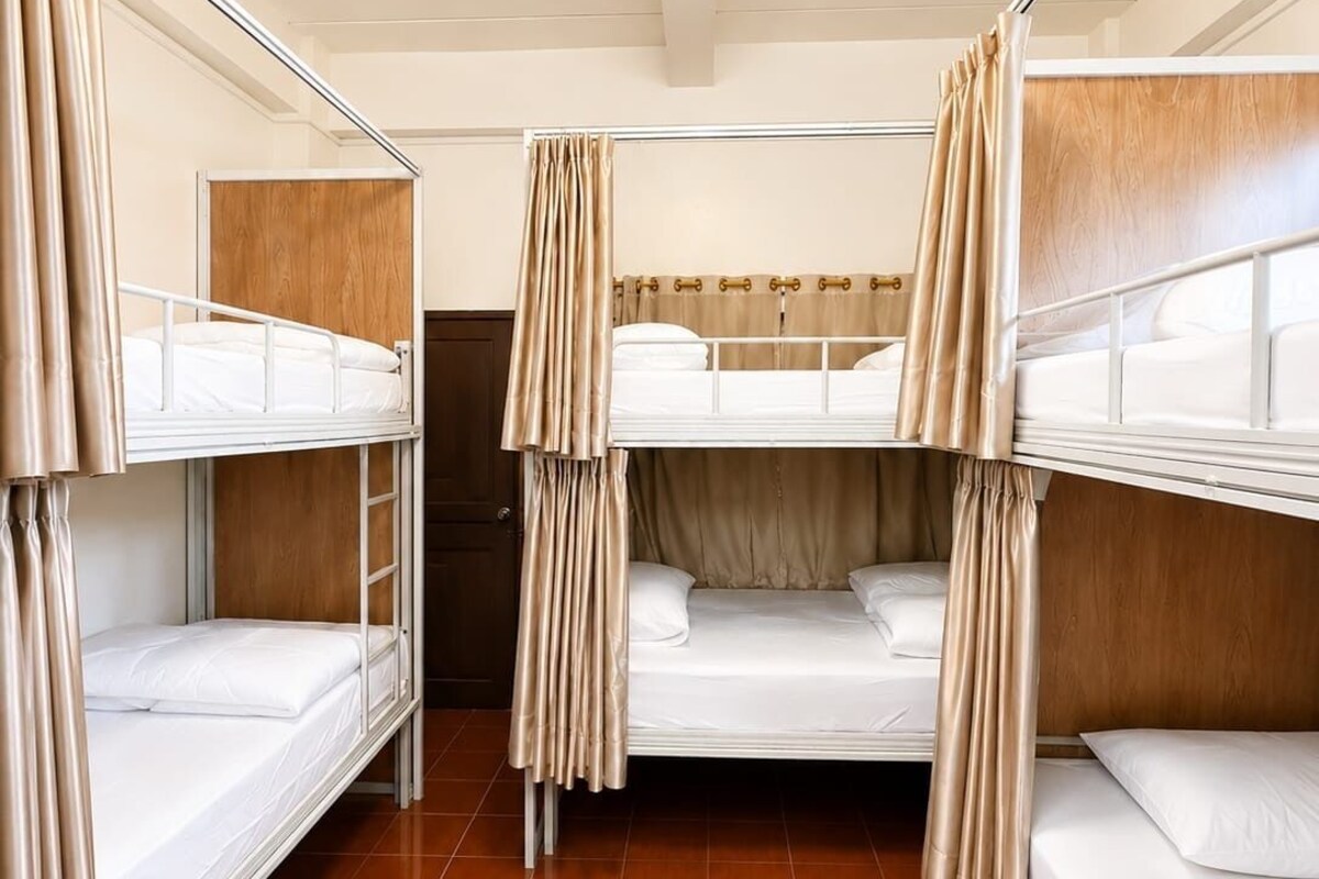 Una habitació amb lliteres, un panell de fusta al capçal i una làmpada al sostre.