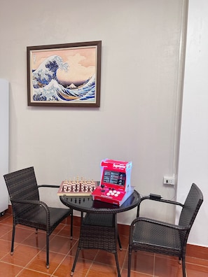 A room with a traditional Japanese wave painting, a chessboard, and a red electronic game console. - Green Hill Hostel (Vientiane)