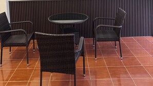 Un espace salon avec une table ronde et quatre chaises, une œuvre d’art fixée au mur et un panneau décoratif vertical.