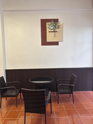 Un área de descanso con una mesa redonda y cuatro sillas, una obra de arte colgada en la pared, y un diseño de panel vertical.