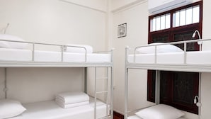 Una habitació de dormitori amb lliteres, una finestra amb marc de fusta i un aparell d'aire condicionat.