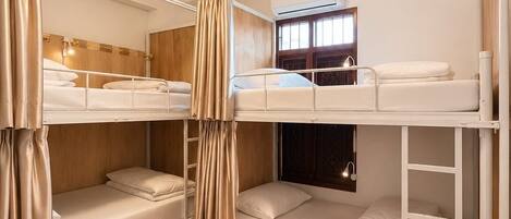 A bunk bed room with a window, curtains, and a ceiling light.