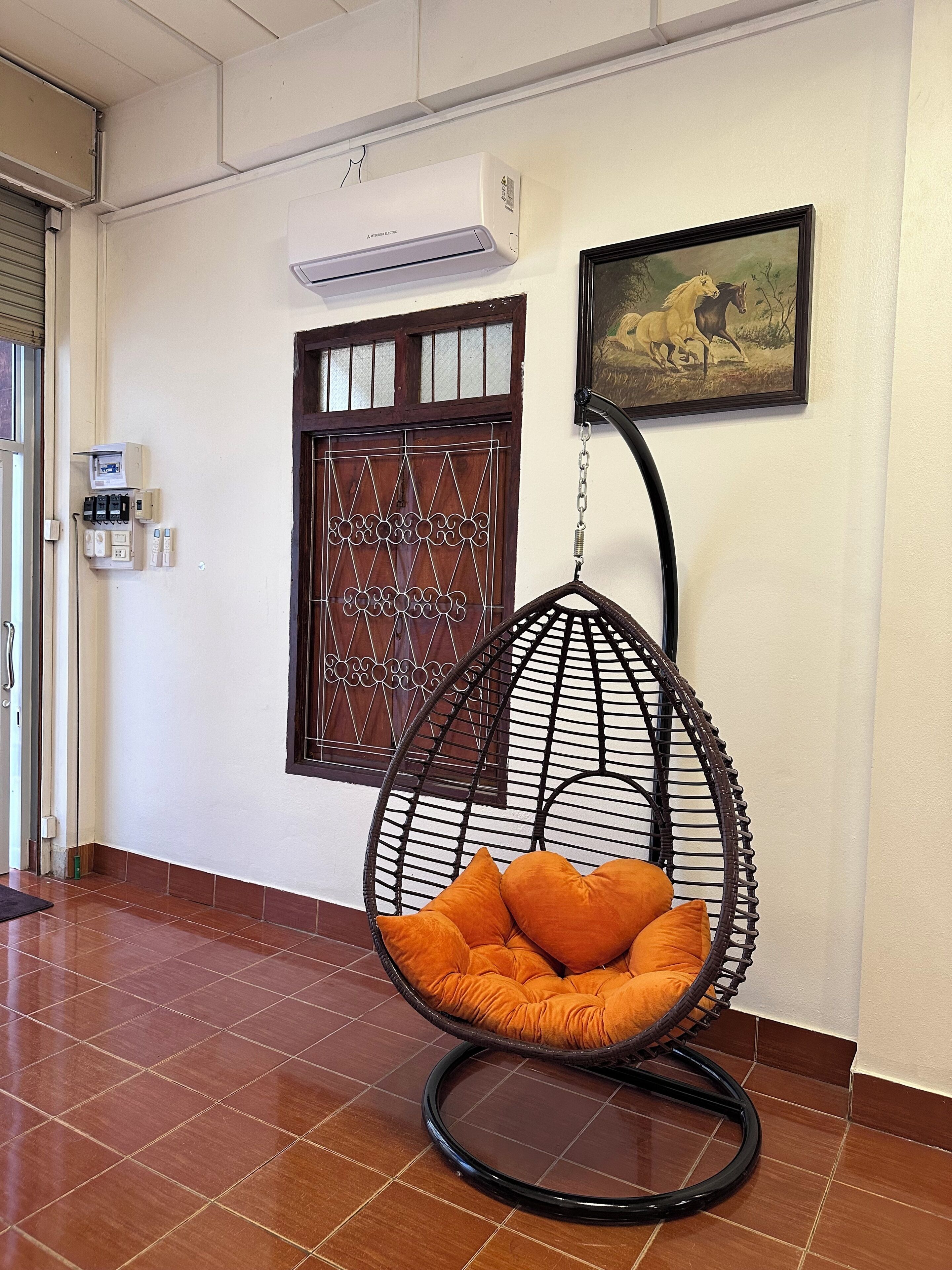 A room with a hanging chair, a door with a decorative glass panel, and an air conditioning unit on the wall.