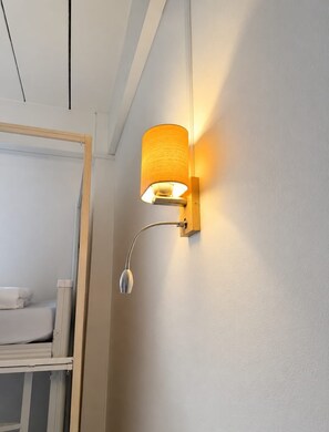 A wall-mounted light fixture with a cylindrical shade and a curved arm, positioned above a white surface, likely a mirror. - Green Hill Hostel (Vientiane)