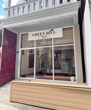 A hotel entrance with a sign reading 'GREEN HILL HOSTEL Fresh. Clean. Comfortable.'