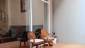Une terrasse en bois avec deux chaises en osier et une plante en pot.