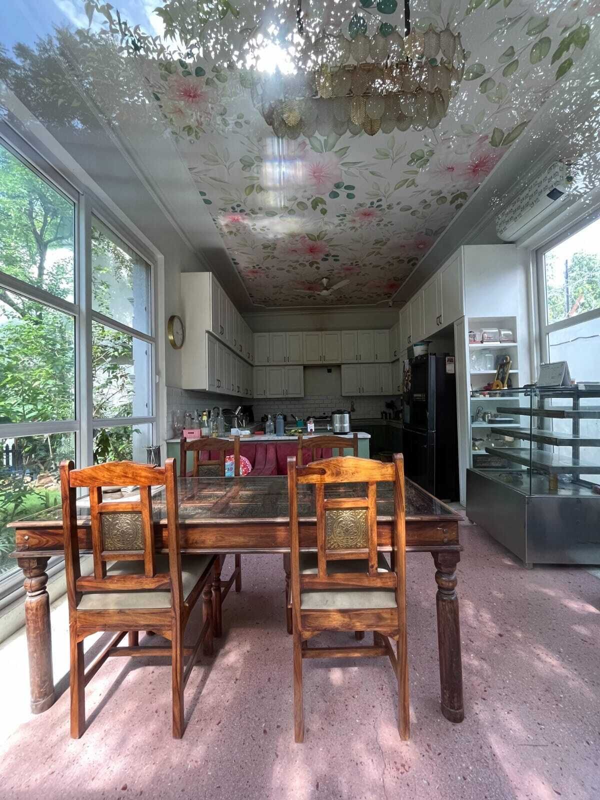 A kitchen with a dining table and chairs, large windows, and a decorative ceiling.