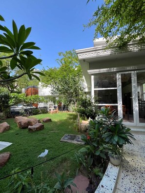 A building with a glass door entrance, a paved pathway, and a grassy area with rocks and plants.