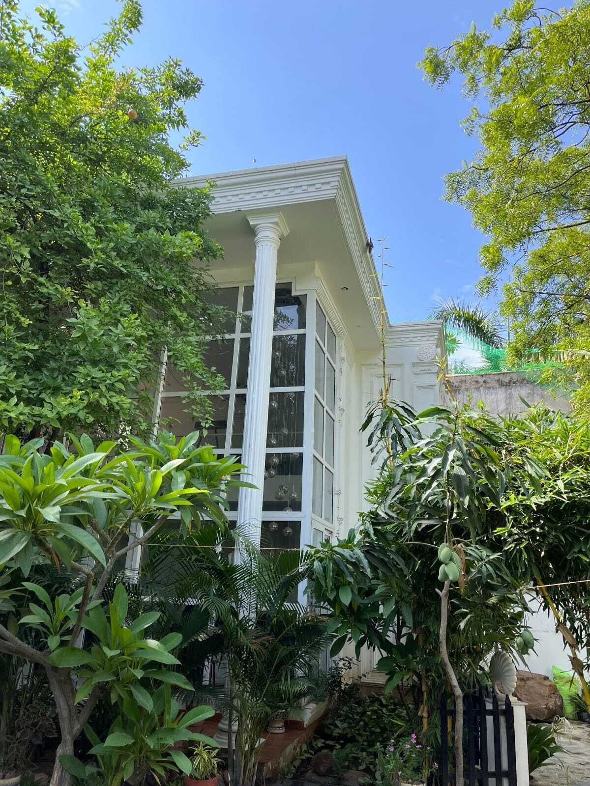 Un edificio con fachada blanca, ventanas grandes y una columna.