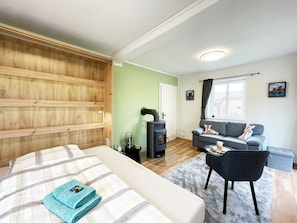 A bedroom with a bed, a wooden headboard, a grey sofa, a black chair, and a window with curtains. - Vrbo Property (Bohlsen)