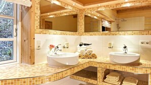 Een badkamer met twee wasbakken, een grote spiegel en een raam.
