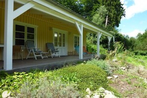 A yellow building with a covered porch, two chairs, and a small table. - Holiday home with 1 bedroom (Groß Zecher)