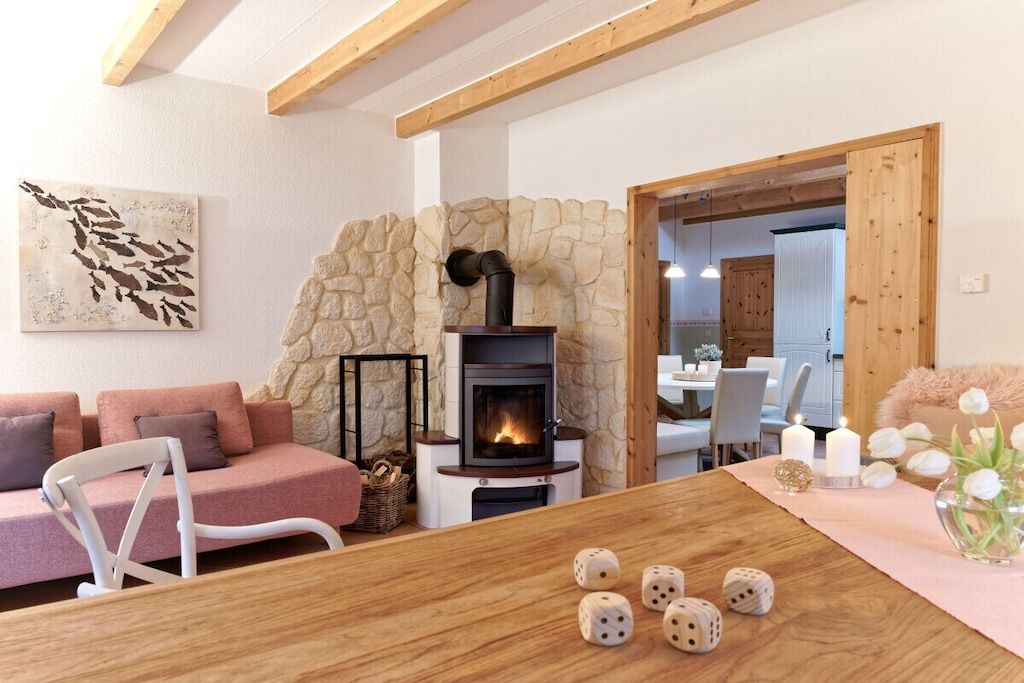A cozy living room with a stone wall, a fireplace, a dining table with dice, and a sofa.