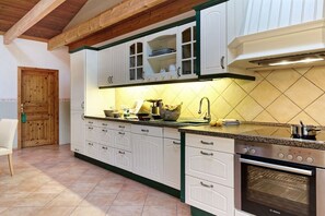 A kitchen with white cabinets, a Bosch oven, and a wooden door. - Holiday home with 1 bedroom (Groß Zecher)
