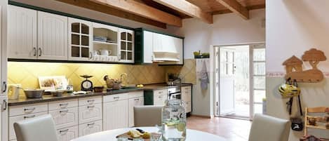 Una cocina con armarios blancos, una mesa redonda para comer y una planta colgante.
