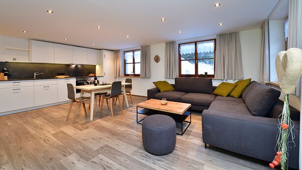 En moderne opholdsstue med køkken, spiseplads og siddeområde.