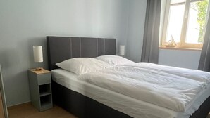 Ein modernes Schlafzimmer mit einem großen Bett, einem Nachttisch und einem Fenster mit Vorhängen.