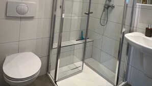 Ein modernes Badezimmer mit einer Duschkabine, einer Toilette und einem Waschbecken.