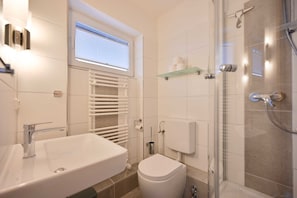 Une salle de bain moderne avec un lavabo blanc, des toilettes et une douche à parois de verre.