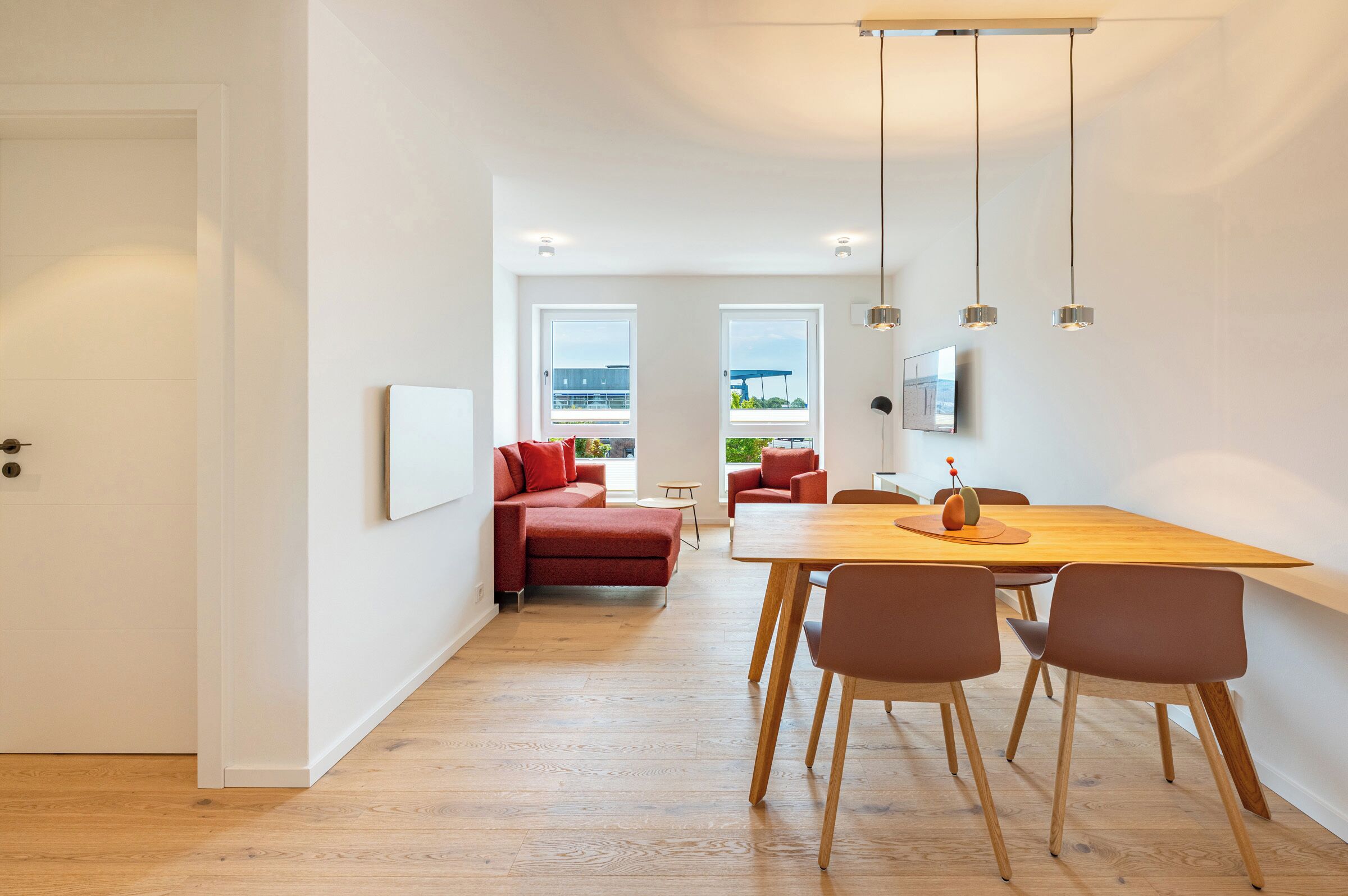 Ein modernes Interieur mit Essbereich, einer Couch und einem an der Wand befestigten Fernseher.