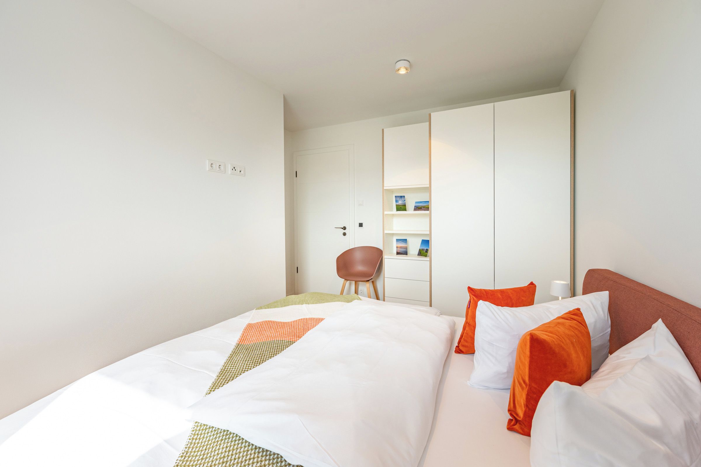 Ein Hotelzimmer mit einem Bett, einem Sessel, einem Kleiderschrank und einem Nachttisch.