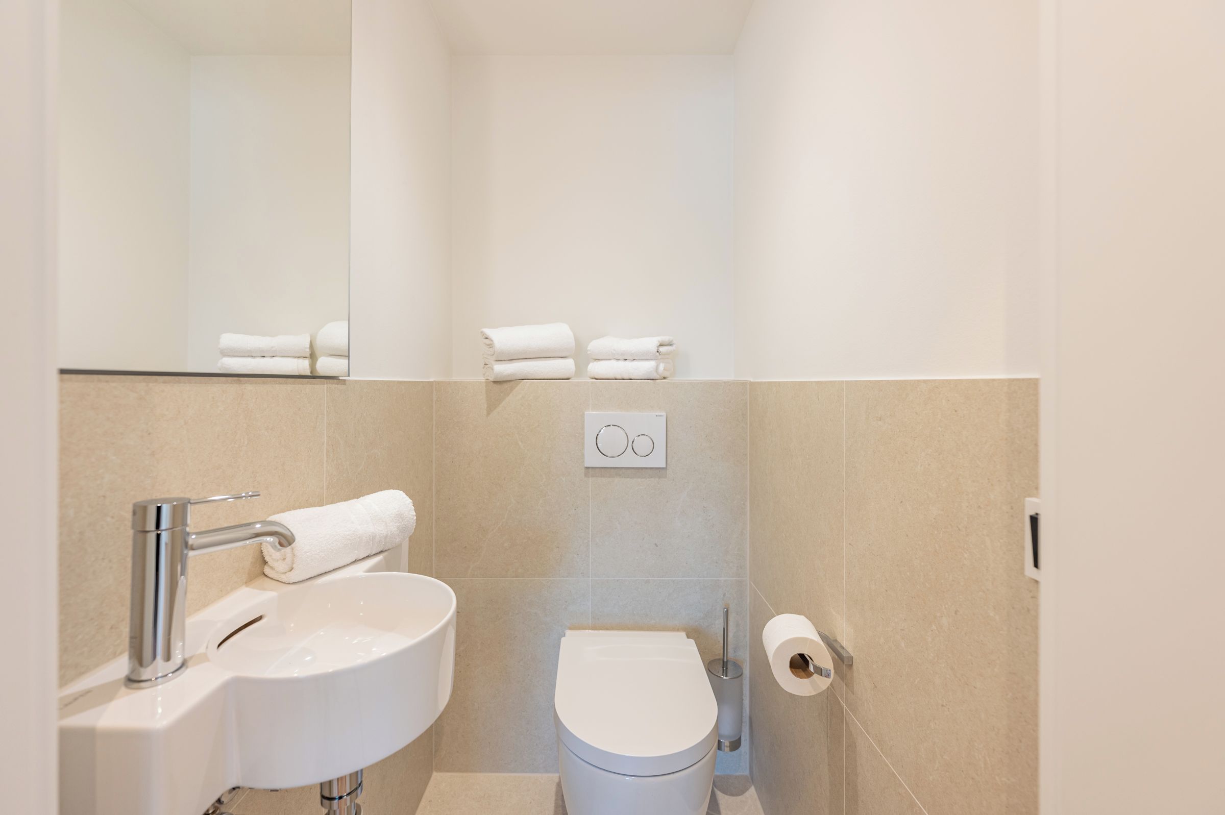 Une petite salle de bain moderne, équipée d’un lavabo, de toilettes et d’un porte-serviettes.