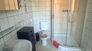 Ein Badezimmer mit einem weißen Waschbecken, einer Toilette und einer Duschkabine.