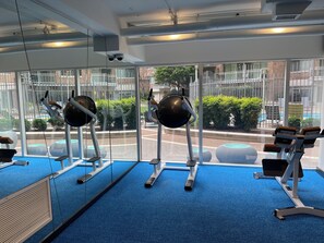 Ein Fitnessraum mit Trainingsgeräten, großen Fenstern und Blick nach draußen.