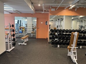 Ett gym med utrustning för styrketräning, bänkar och en vägg med speglar.