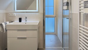 Un bagno moderno con un ampio specchio, un lavandino e uno spazio doccia.