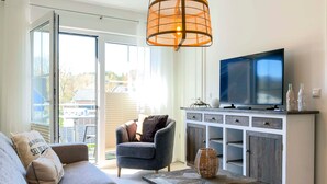Un soggiorno con divano, poltrona, tavolino, televisore e un mobile contenente oggetti decorativi.